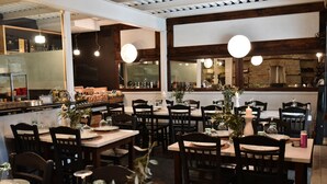 A restaurant interior with wooden tables and chairs, candle centerpieces, and hanging pendant lights. - Culinary Boutique Hotel Kladi Elias (Pangaio)