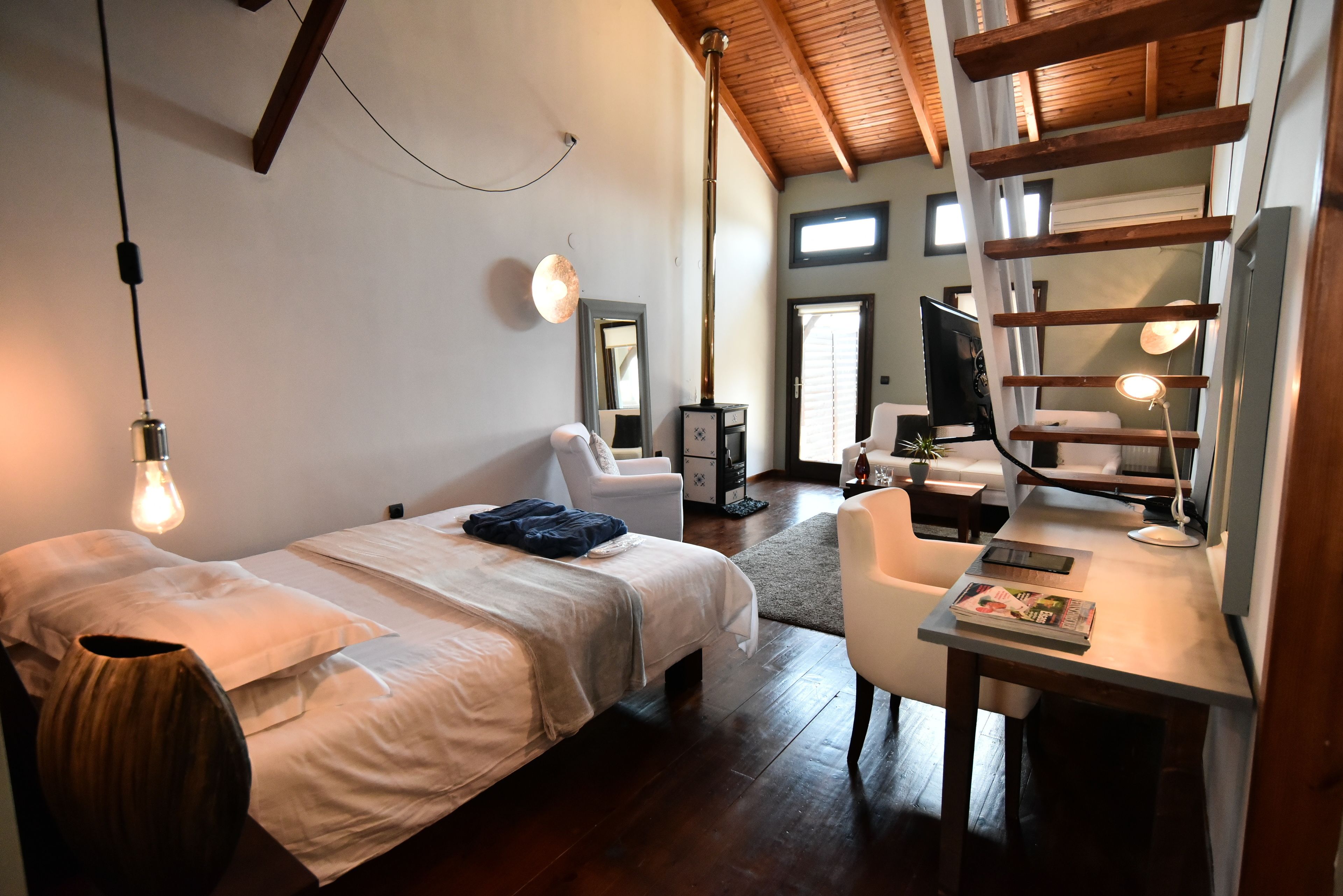 Un dormitorio con cama, mesita de noche, lámpara y espejo.
