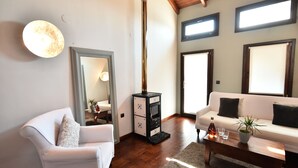 A living room with a white sofa, a white armchair, a wooden coffee table, and a large mirror. - Culinary Boutique Hotel Kladi Elias (Pangaio)