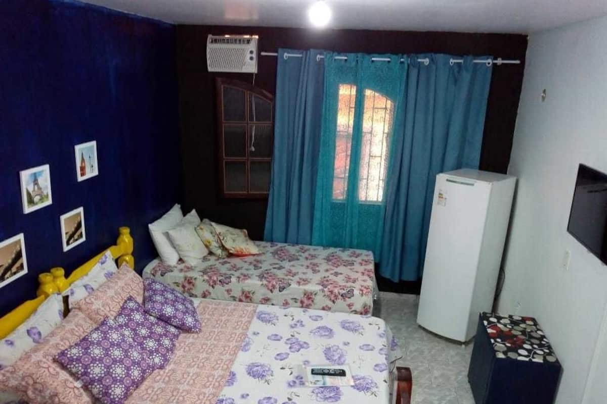 Ein Schlafzimmer mit zwei Betten, einem Kühlschrank und einem Fernseher.