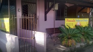 Un edificio con un letrero amarillo, una verja metálica y plantas en macetas.