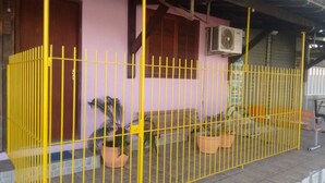 Un edificio con cerca amarilla, plantas en macetas y una escalera que lleva a una puerta.