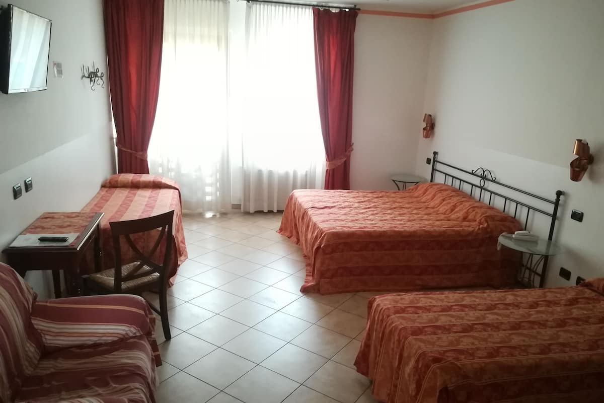 Een hotelkamer met twee bedden, een tafeltje, een stoel, een bureau en een spiegel.