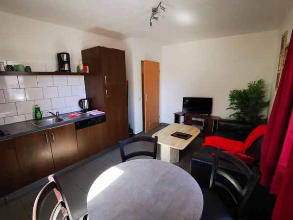 A compact living space with a kitchenette, a dining area, and a seating area with a TV. - Stadtdomizil (Augsburg)