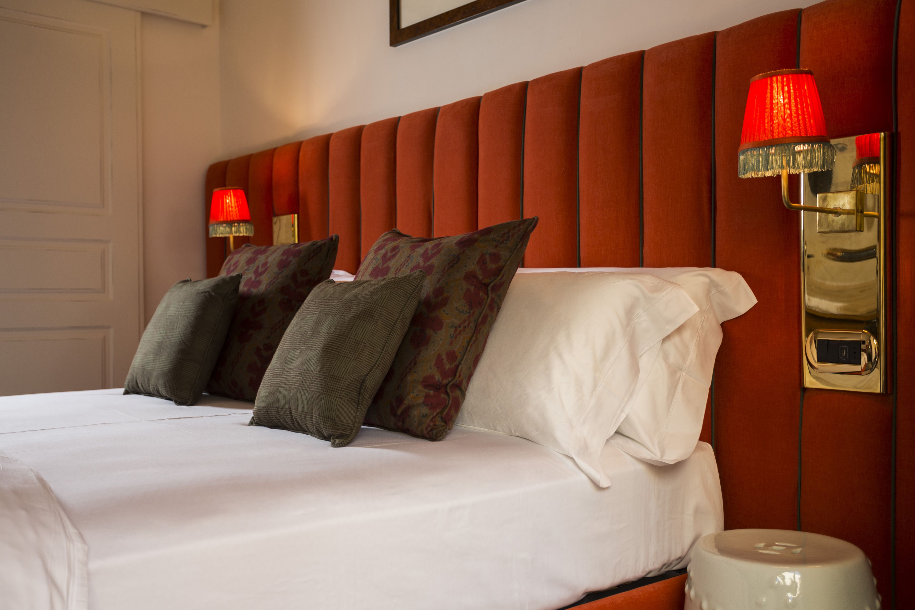 Ein Hotelzimmer mit einem großen Bett, einem roten Kopfteil und einer Wandleuchte.