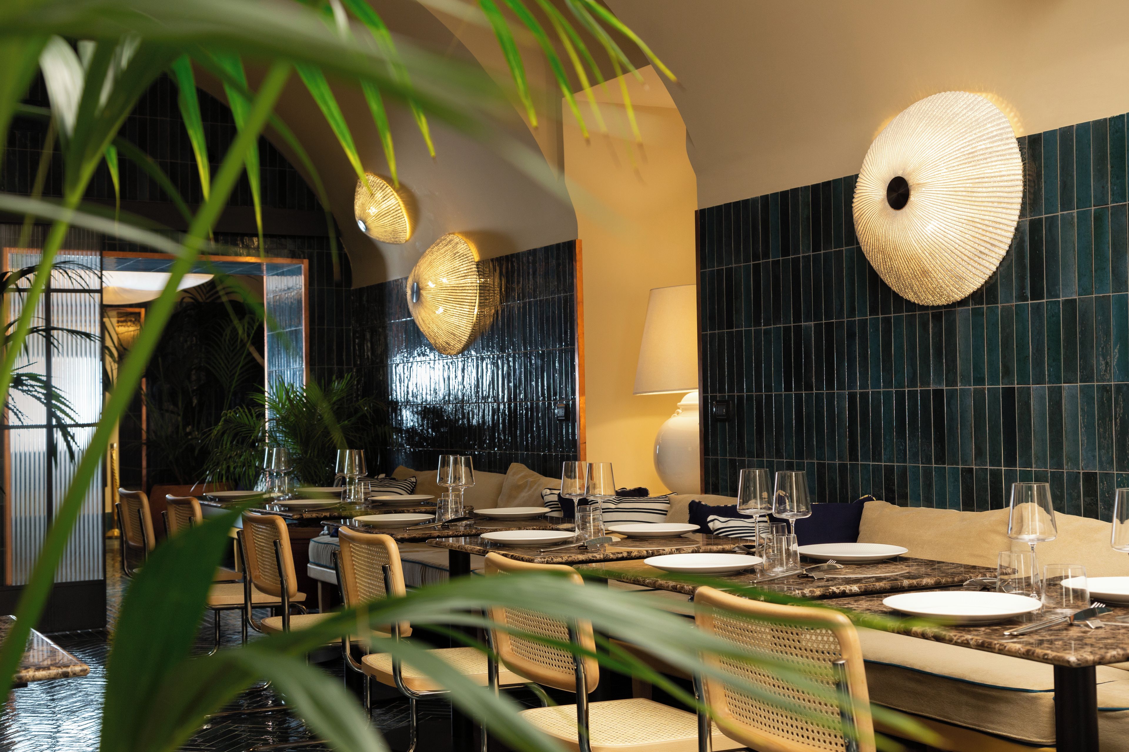 A restaurant with a long dining table, chairs, and a wall with a textured pattern.