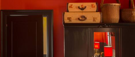 A dark wooden cabinet with a red lamp, a mirror, and vintage suitcases.