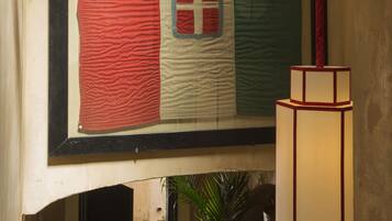 A framed flag with a red, white, and green design, a staircase with a checkered floor, and a potted plant.