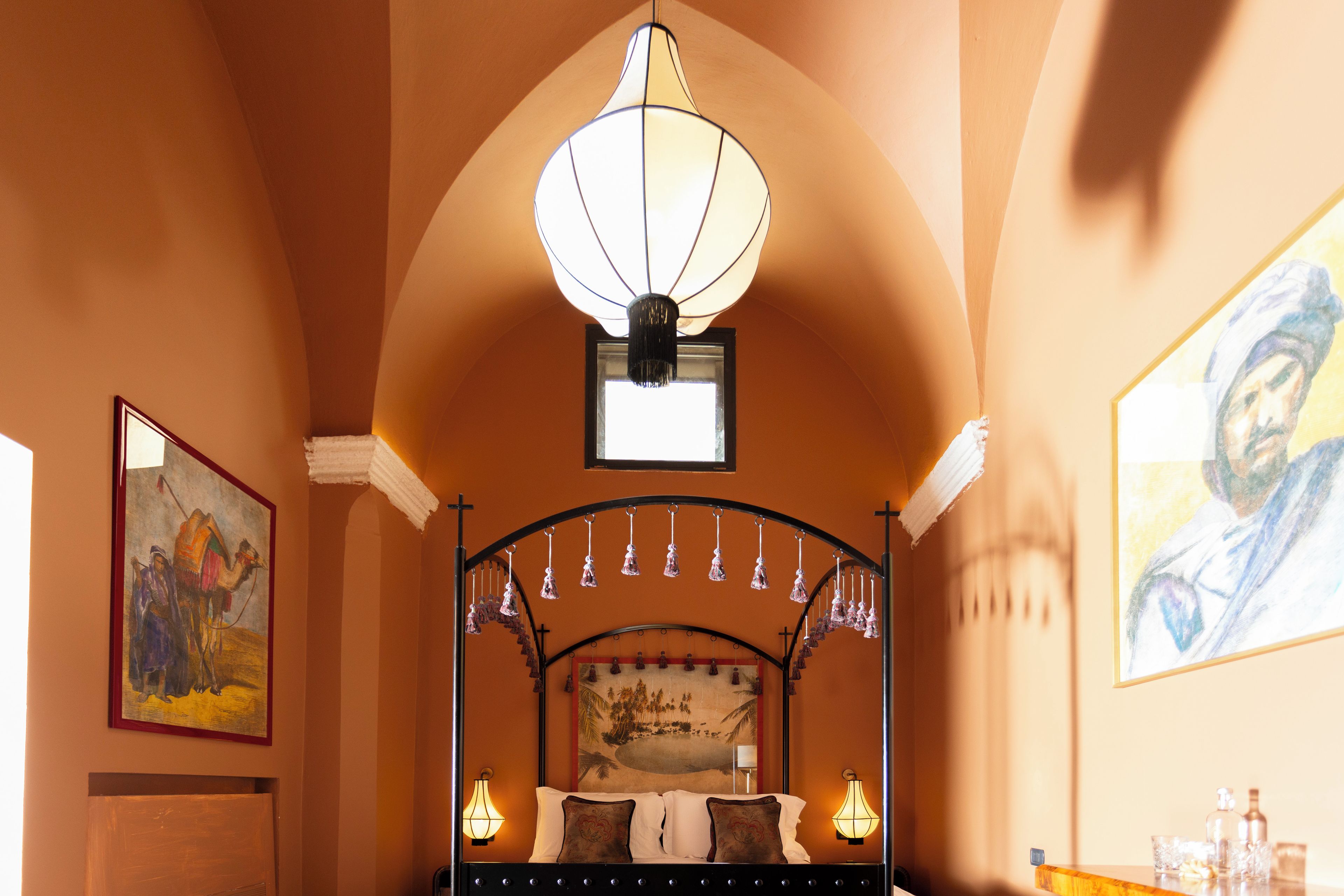 Une chambre à coucher avec un lit, un luminaire suspendu et un tableau au mur.