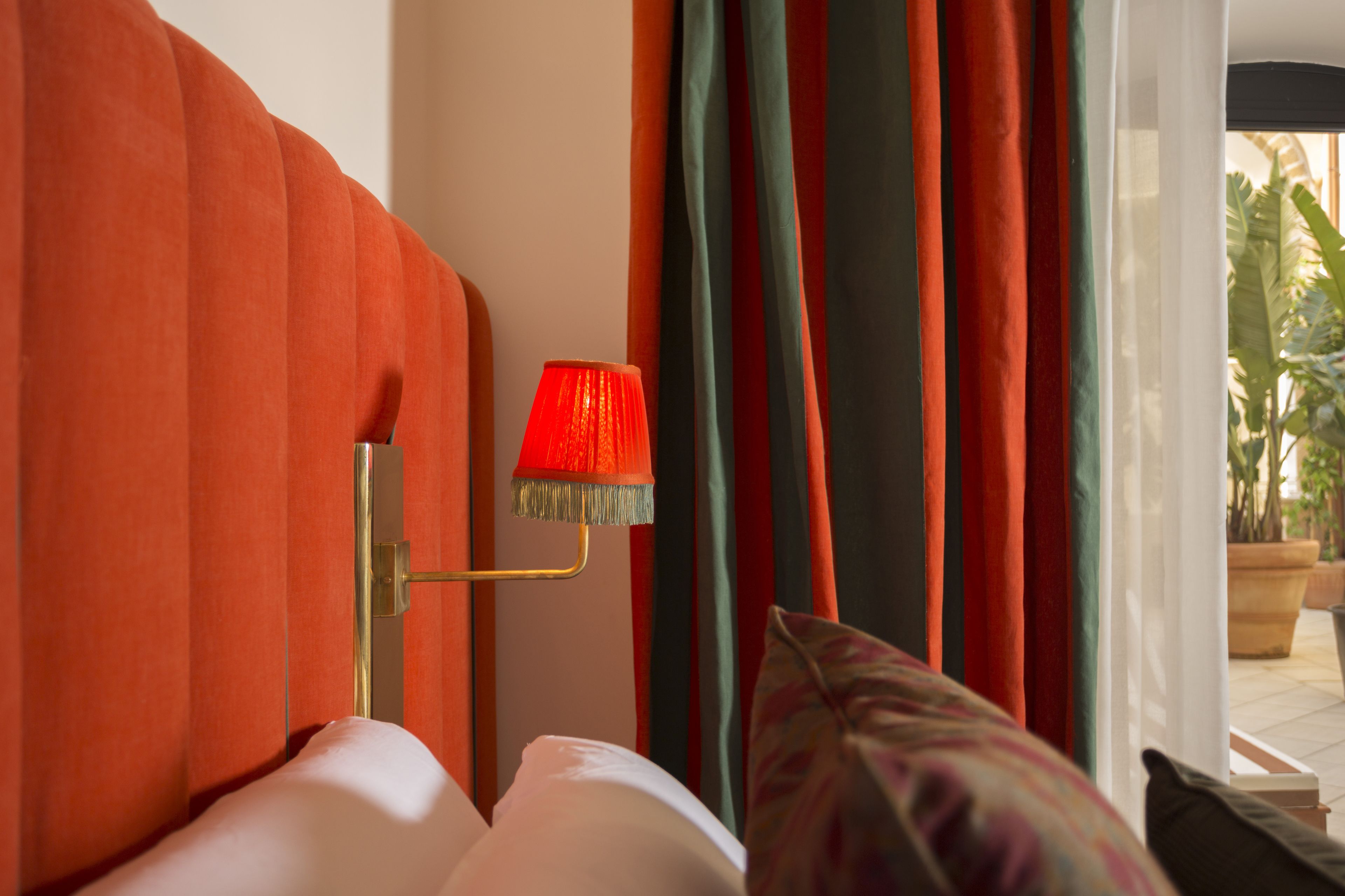 Una habitación de hotel con una cama, una lámpara roja y cortinas.