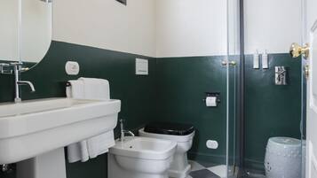 A bathroom with a white sink, two toilets, a shower with a glass door, and a checkered floor.