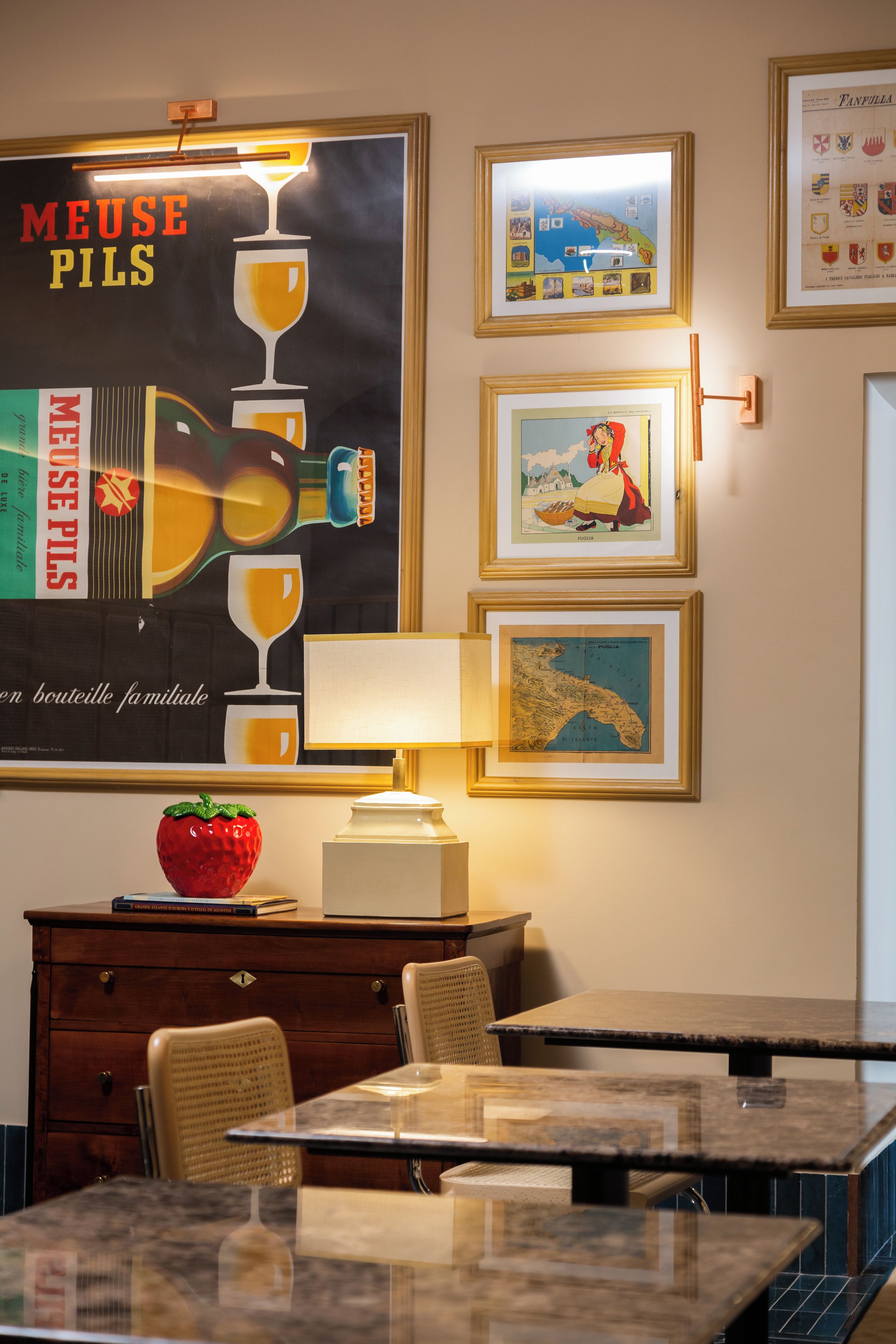 Un coin repas comprenant une table, des chaises, une lampe, un bol décoratif et une affiche accrochée au mur.