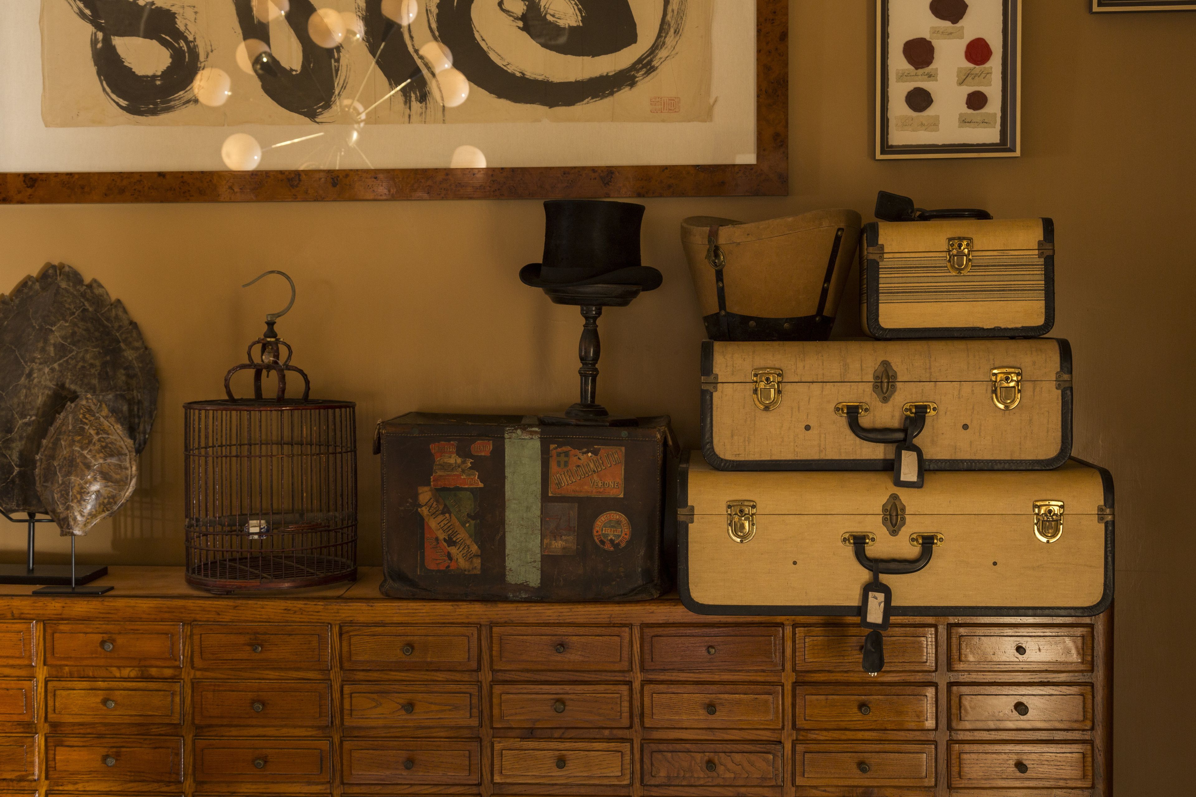 Une commode en bois avec de nombreux tiroirs et une pile de valises anciennes.