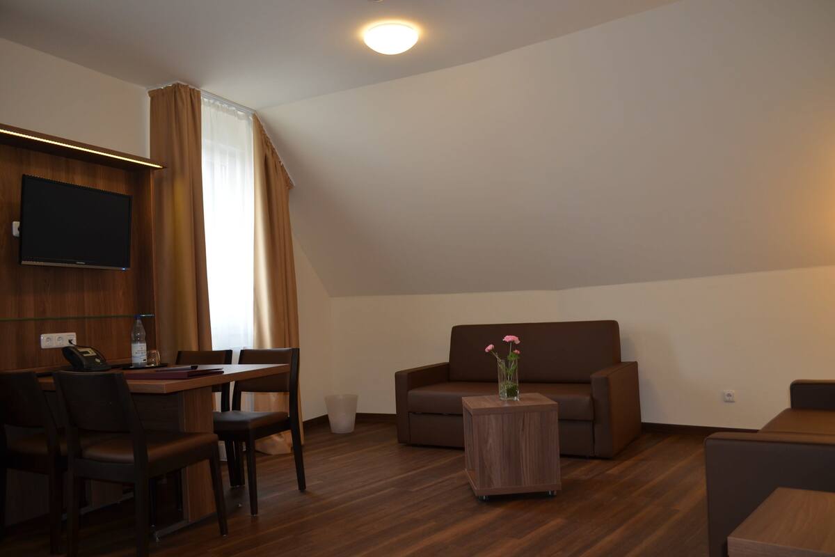 Una sala de estar moderna con televisor de pantalla plana, un sofá, una mesa de centro y un comedor con sillas y una mesa.