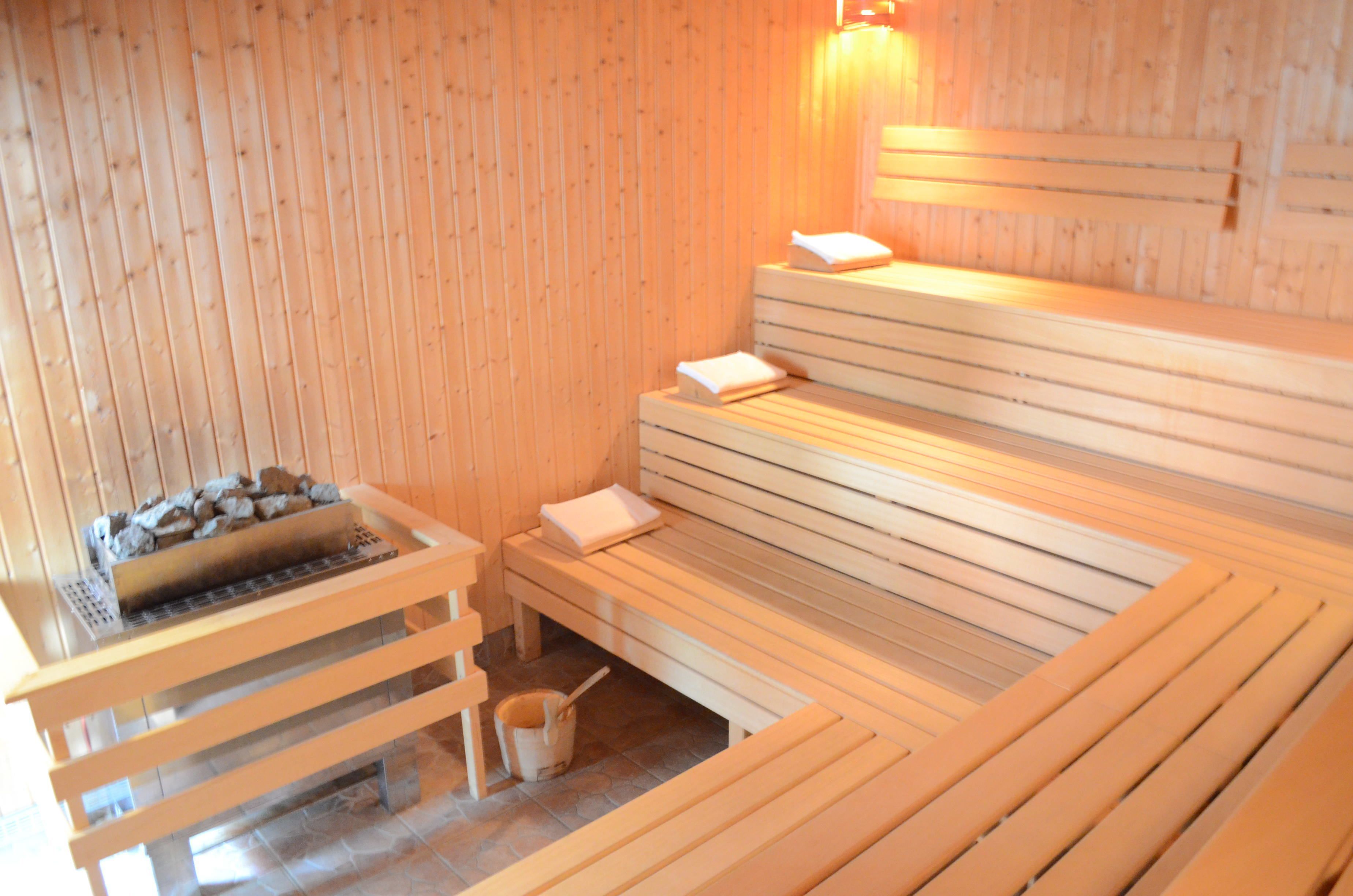 Una sauna de madera con bancos y un hogar de piedra.