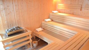 Una sauna de madera con bancos y un hogar de piedra.