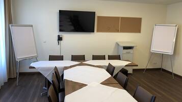 Een vergaderruimte met een lange tafel, stoelen, een whiteboard, een televisie en een telefoon aan de muur.