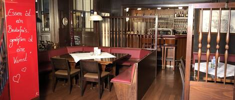Un restaurante con interior de madera, una zona de bar y un letrero rojo con texto.