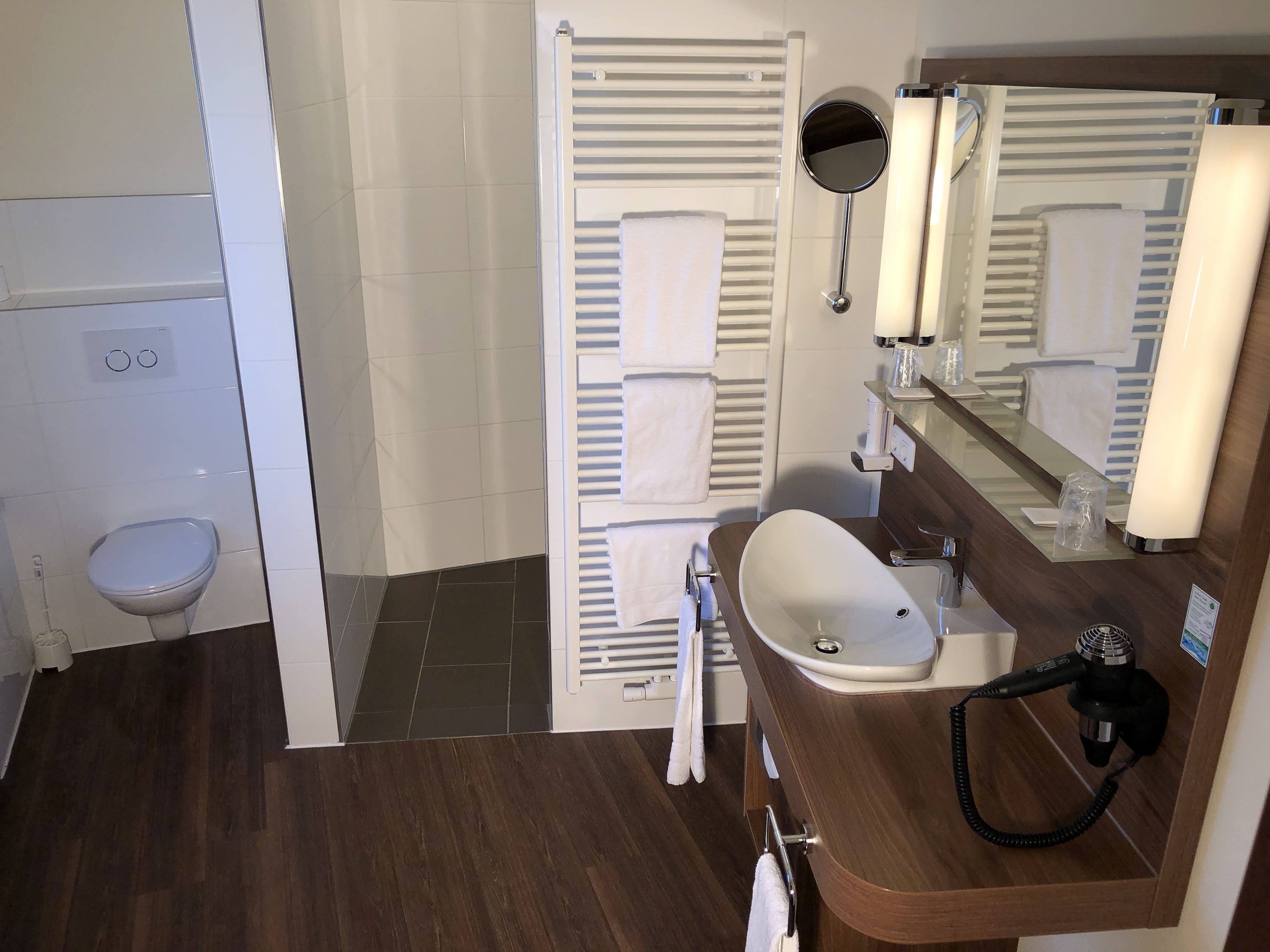 A modern bathroom with a shower, toilet, and sink.