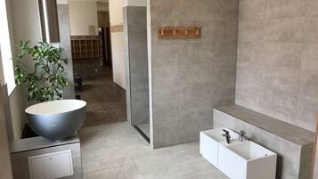 A modern bathroom with a large sink, a bathtub, and a shower area.