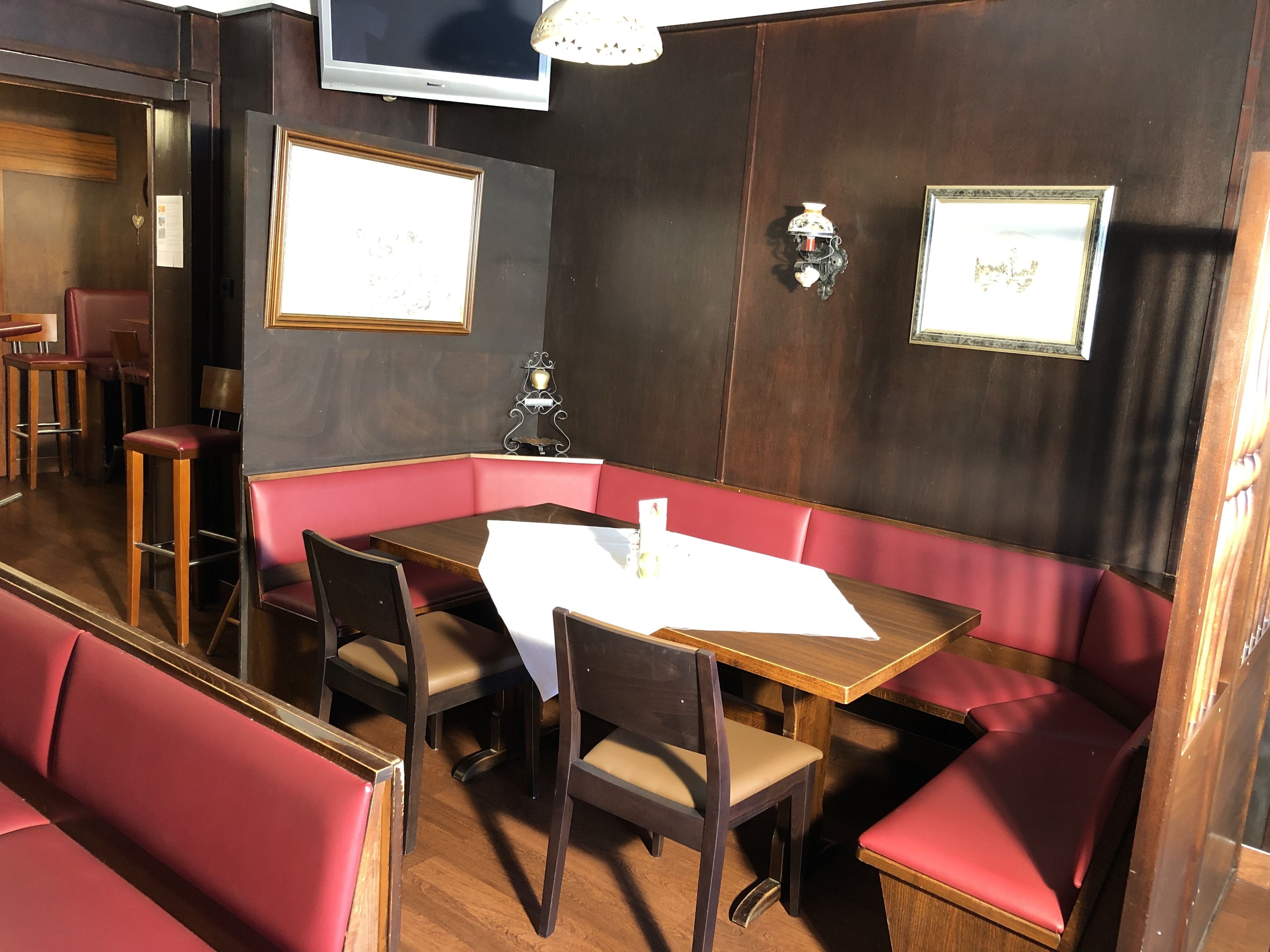 A restaurant with a booth seating area, wooden tables, and red cushioned booths.
