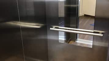 Un ascensore moderno con pareti in metallo e pavimento in legno.