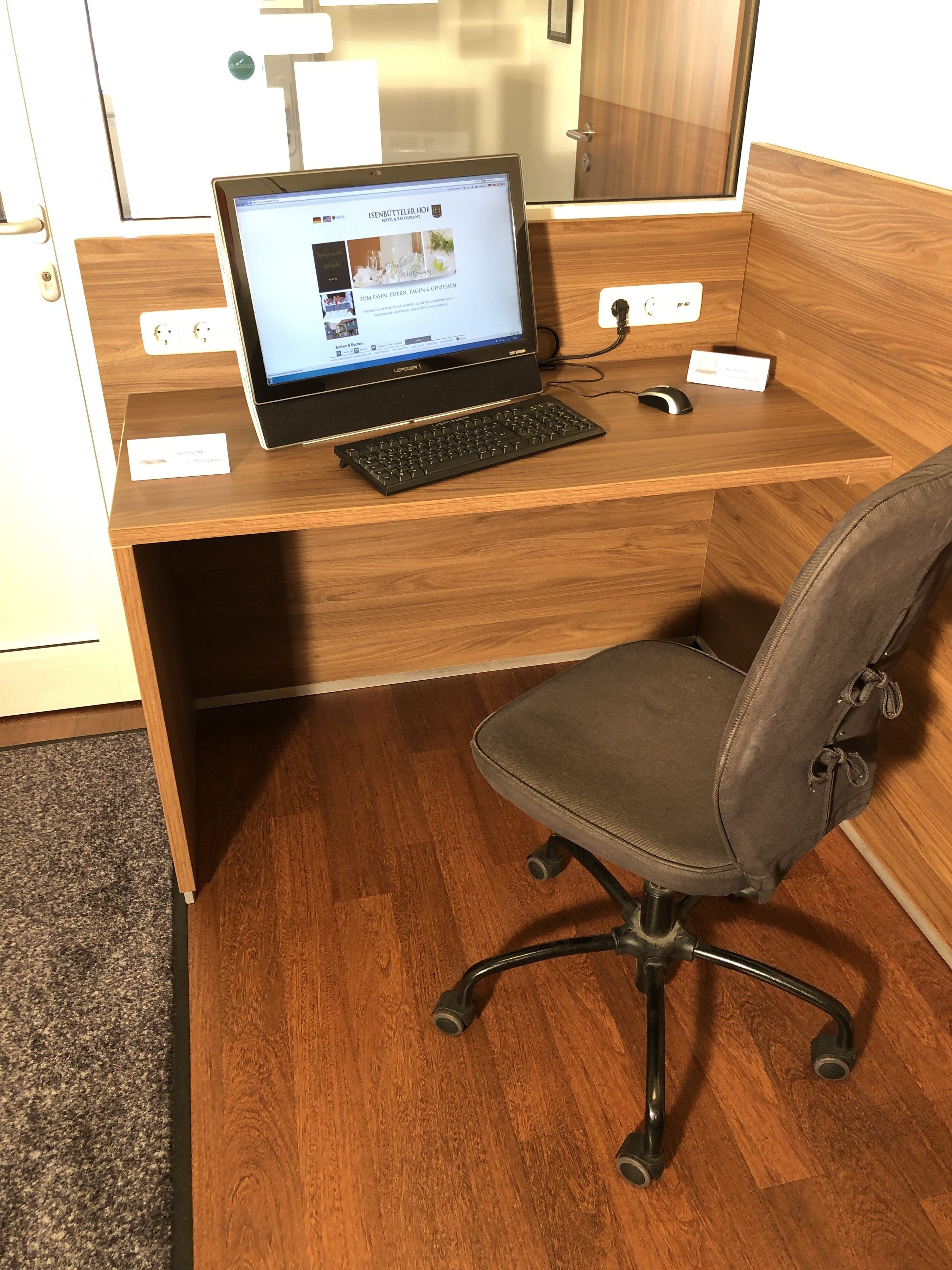 Ein Holztisch mit einem Laptop, einer Tastatur und einer Maus.