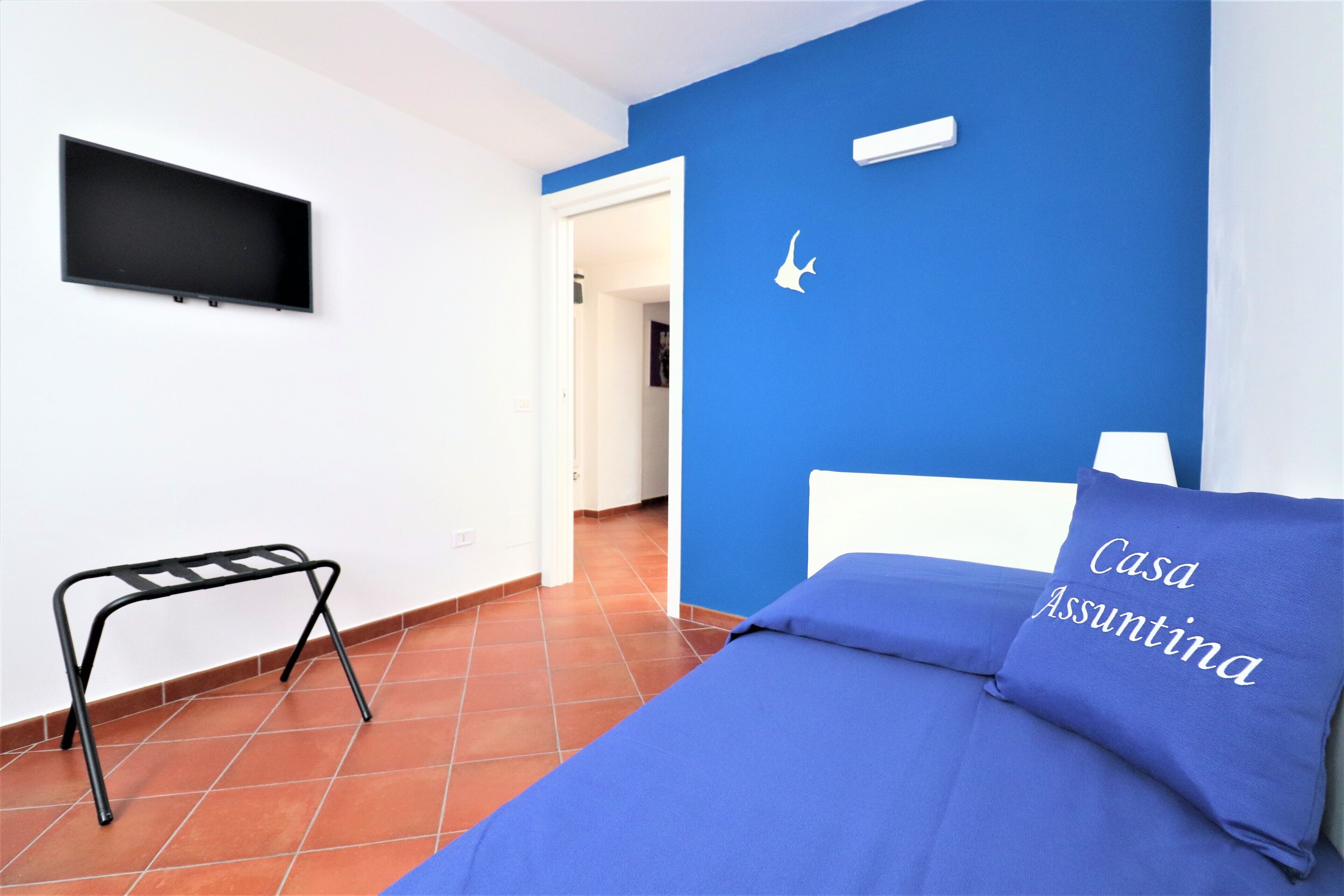 A bedroom with a bed, a TV mounted on the wall, and a small table.