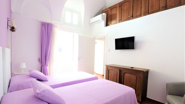 Een slaapkamer met twee bedden, een houten kast, een televisie en een stoel.