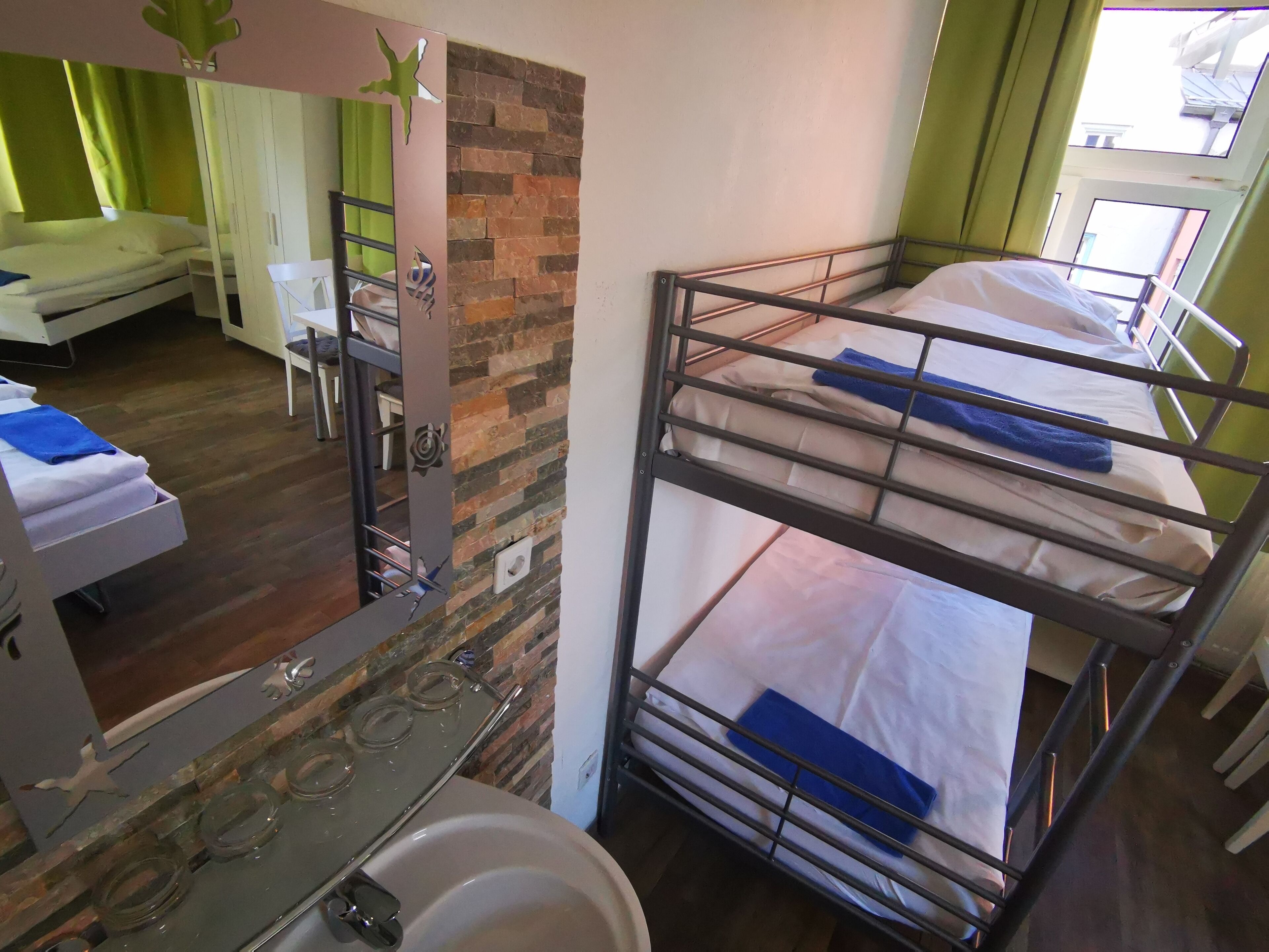 A bunk bed room with a mirror, a sink, and a window.