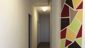 A narrow hallway with wooden flooring and a colorful geometric wall design. - City Hostel (Augsburg)