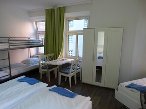 Asuntolan huone, jossa on kerrossängyt, ruokapöytä, tuolit ja vaatekaappi.