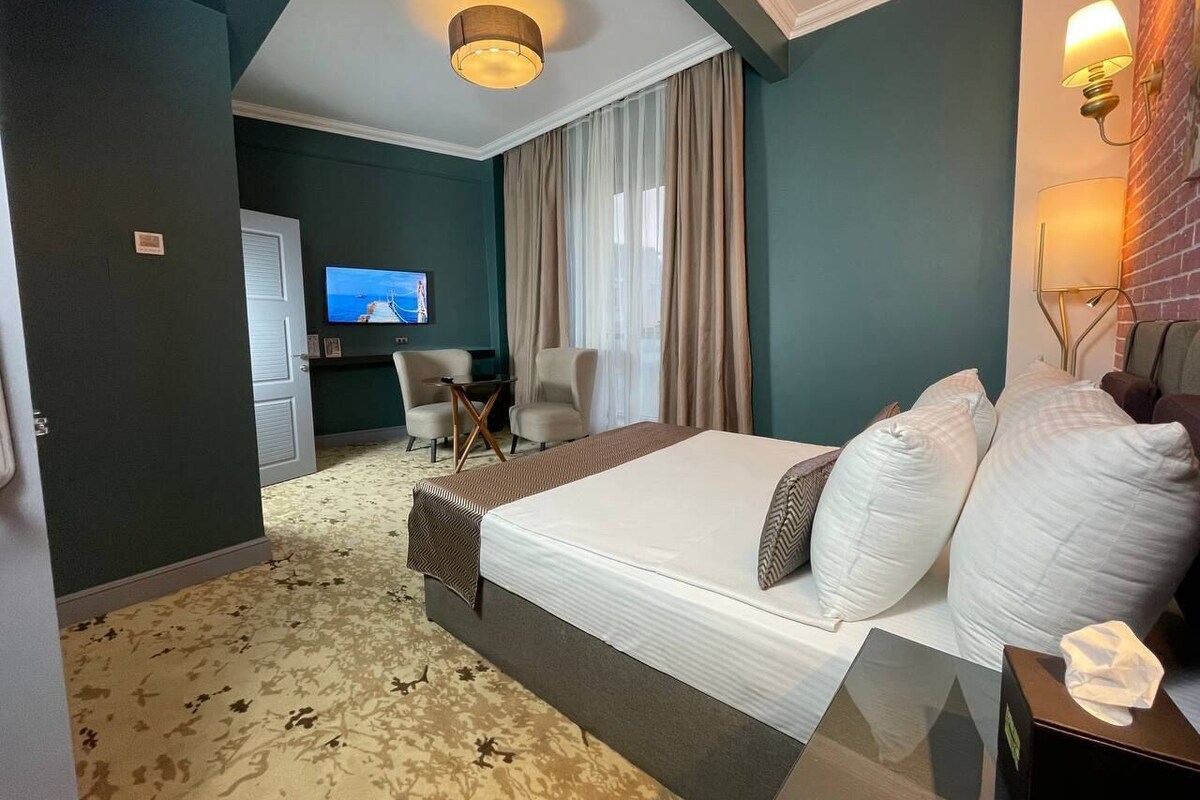 A hotel room with a bed, a TV, a desk, and a chair.