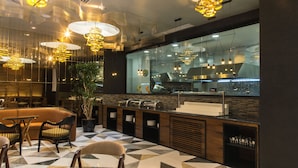 En modern restaurang med ett geometriskt mönstrat klinkergolv, trämöbler och hängande lampor.
