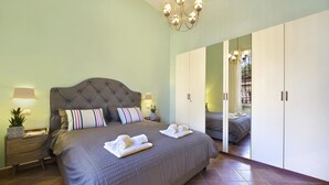 A bedroom with a large bed, bedside tables, a mirror, and a wardrobe. - Henry House (Sorrento)