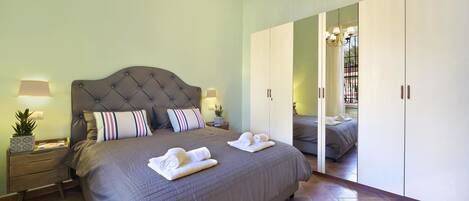 A bedroom with a large bed, bedside tables, a mirror, and a wardrobe.
