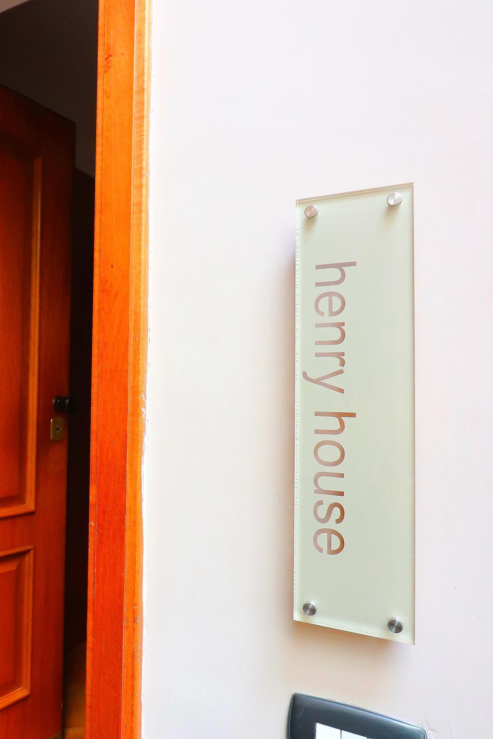 Een bord met de tekst 'henry house' aan een muur bevestigd.