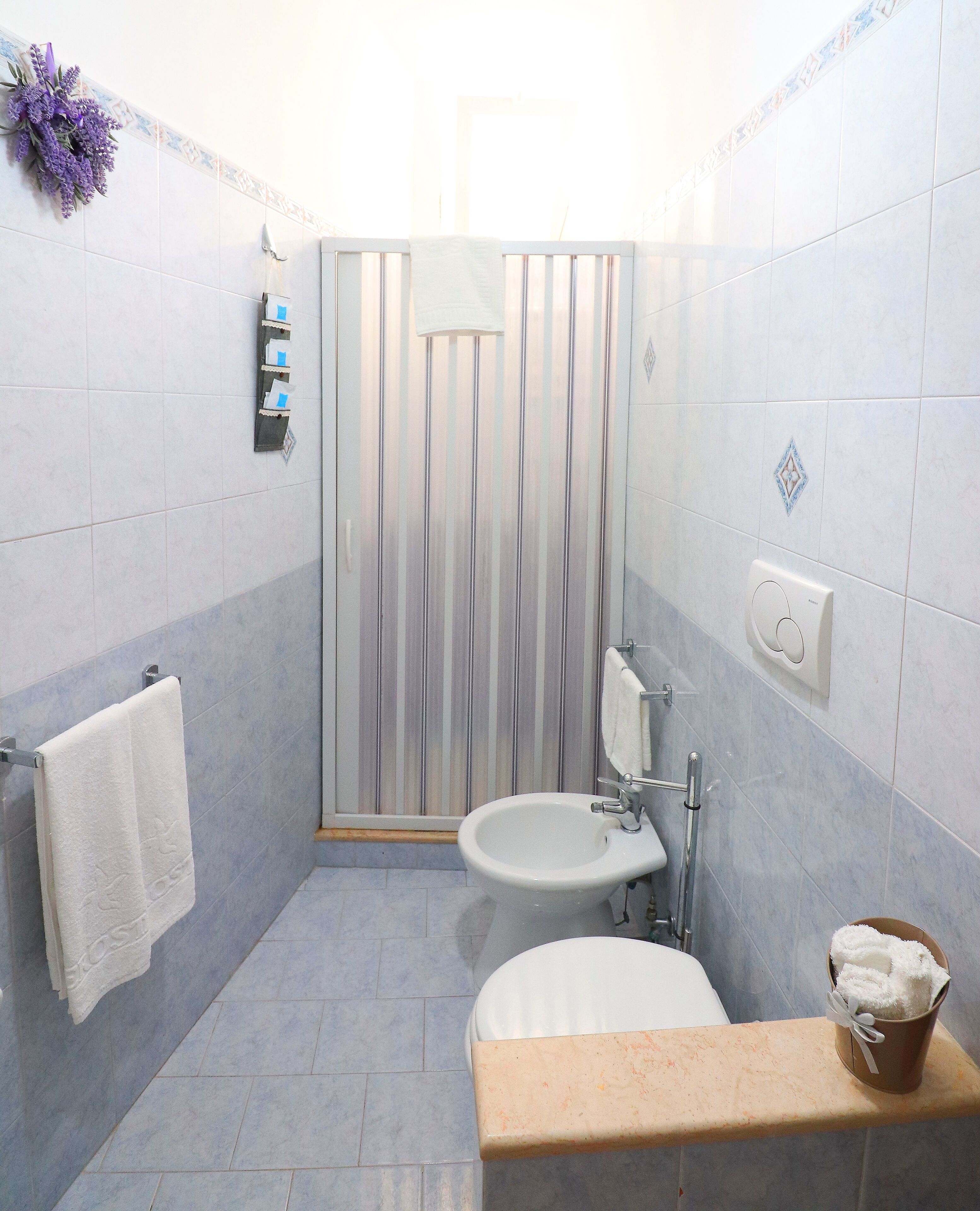 Een badkamer met een douche, toilet, wastafel en een handdoekhouder.