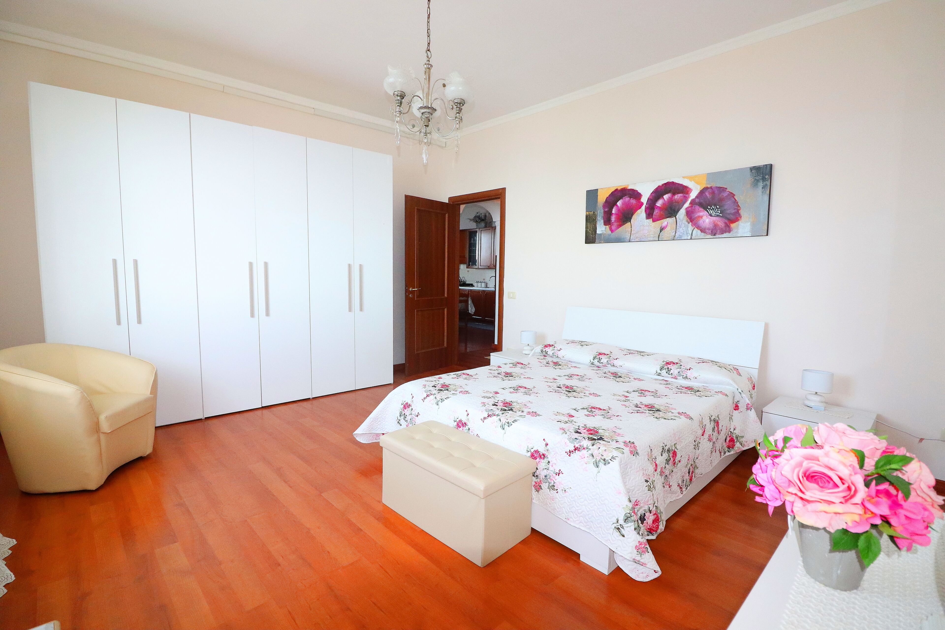 A bedroom with a bed, a chair, a wardrobe, and a painting on the wall.