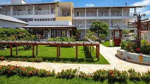 A hotel with multiple floors, outdoor seating area, and a garden with potted plants. - Brisamar Hotel Pousada (Barra de São Miguel)