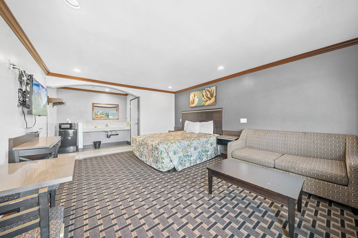 Ein Hotelzimmer mit Bett, Sofa, Schreibtisch und einer kleinen Essecke.