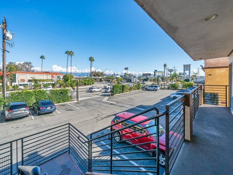 A parking lot with several cars, a gas station, and a building with a balcony.