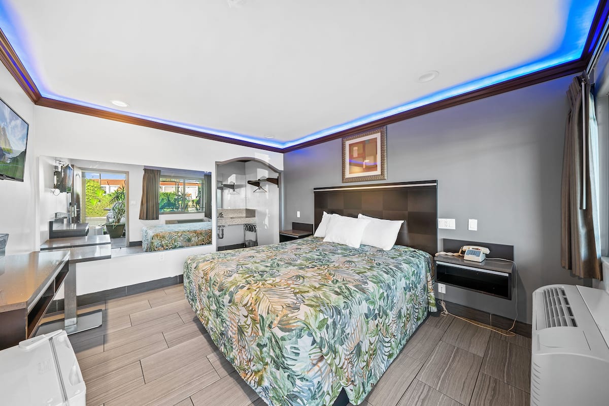 Ein modernes Hotelzimmer mit einem großen Bett, einem Schreibtisch und einer Duschkabine.