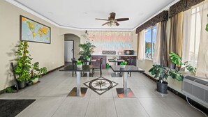 Een moderne hotelentree met een eetgedeelte, plafondventilator, kaart aan de muur en potplanten.