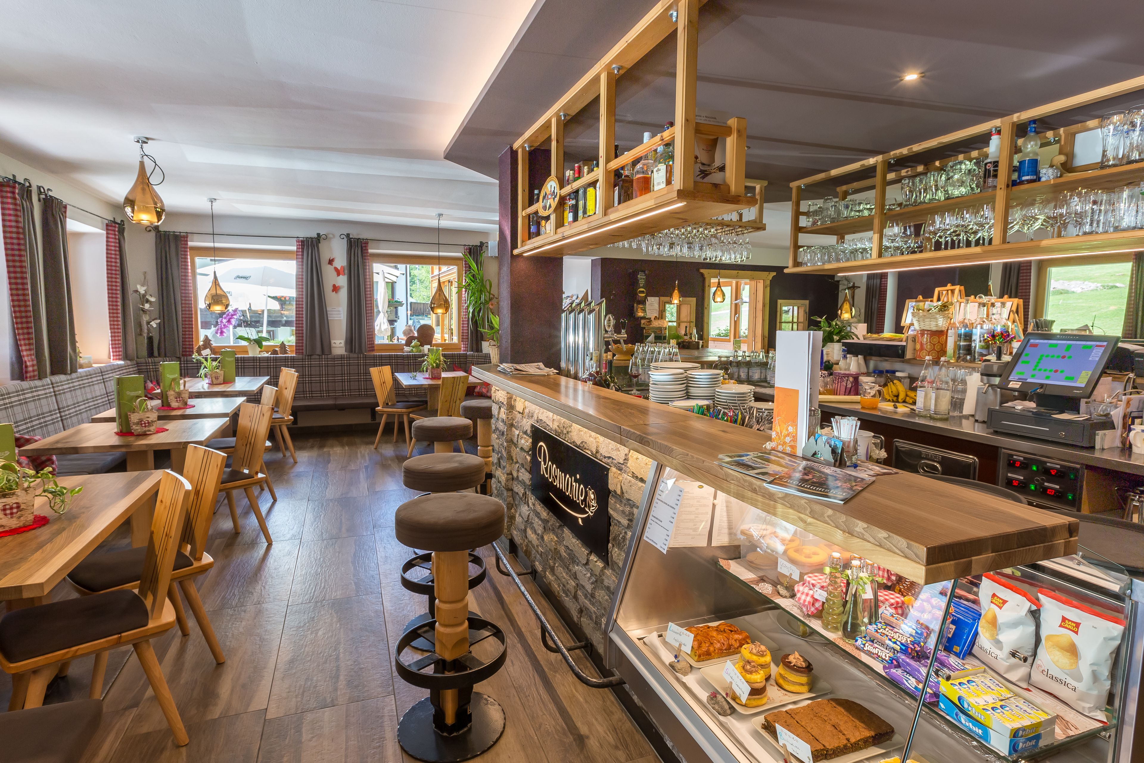 Un restaurante con taburetes de madera, una barra con un menú a la vista y estanterías con cristalería.
