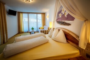A hotel room with two beds, a TV, a small table, and a painting of flowers on the wall. - Wellness- und Genußhotel Rosmarie (Moso in Passiria)