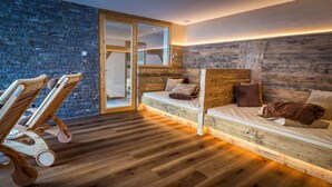 A modern room with a wooden floor, a built-in bench with cushions, and a stone wall. - Wellness- und Genußhotel Rosmarie (Moso in Passiria)