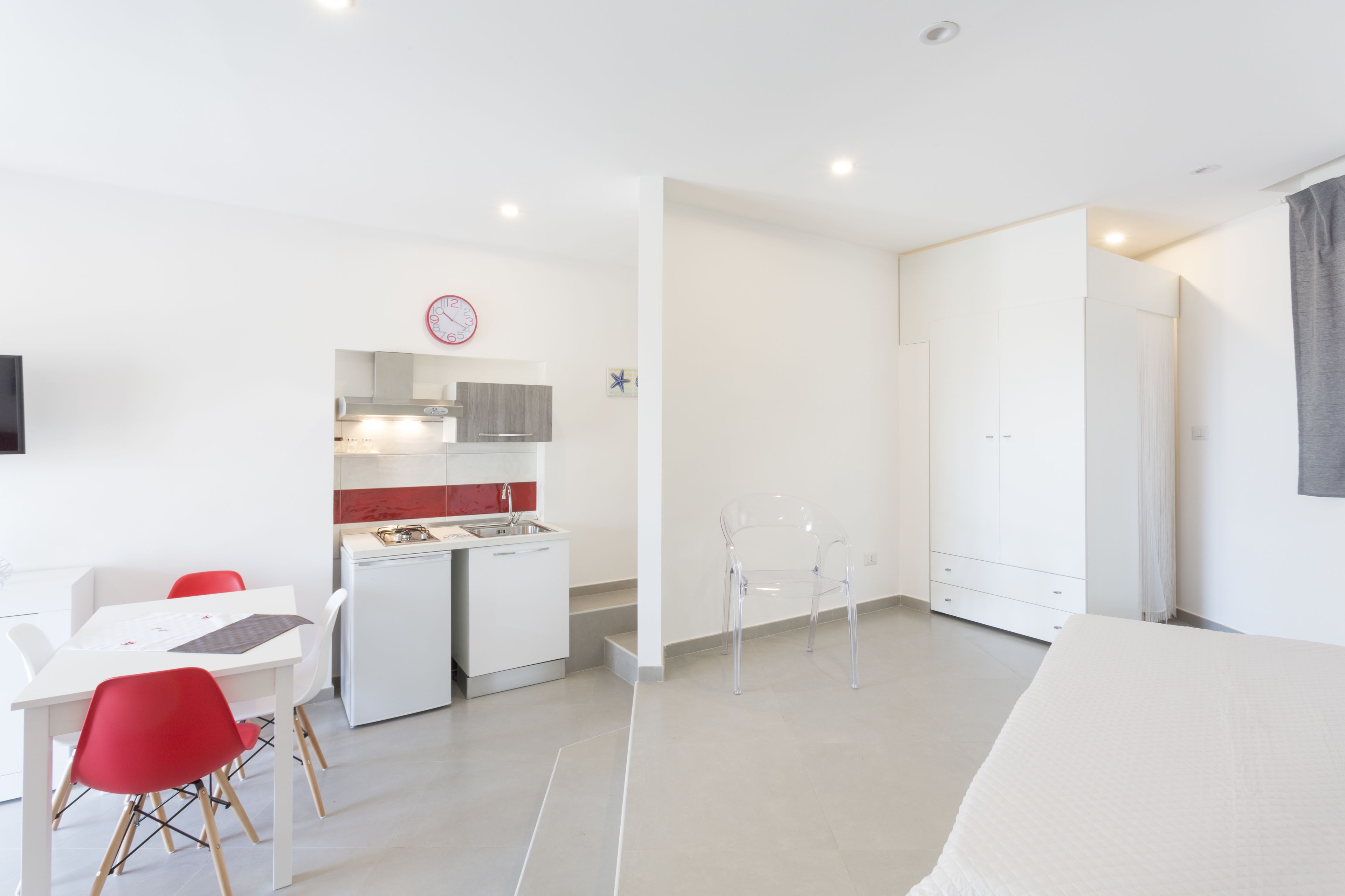 Una habitación moderna y minimalista con comedor, kitchenette y cama.