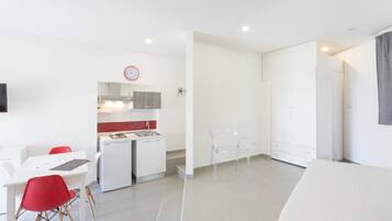 Una habitación moderna y minimalista con comedor, kitchenette y cama.