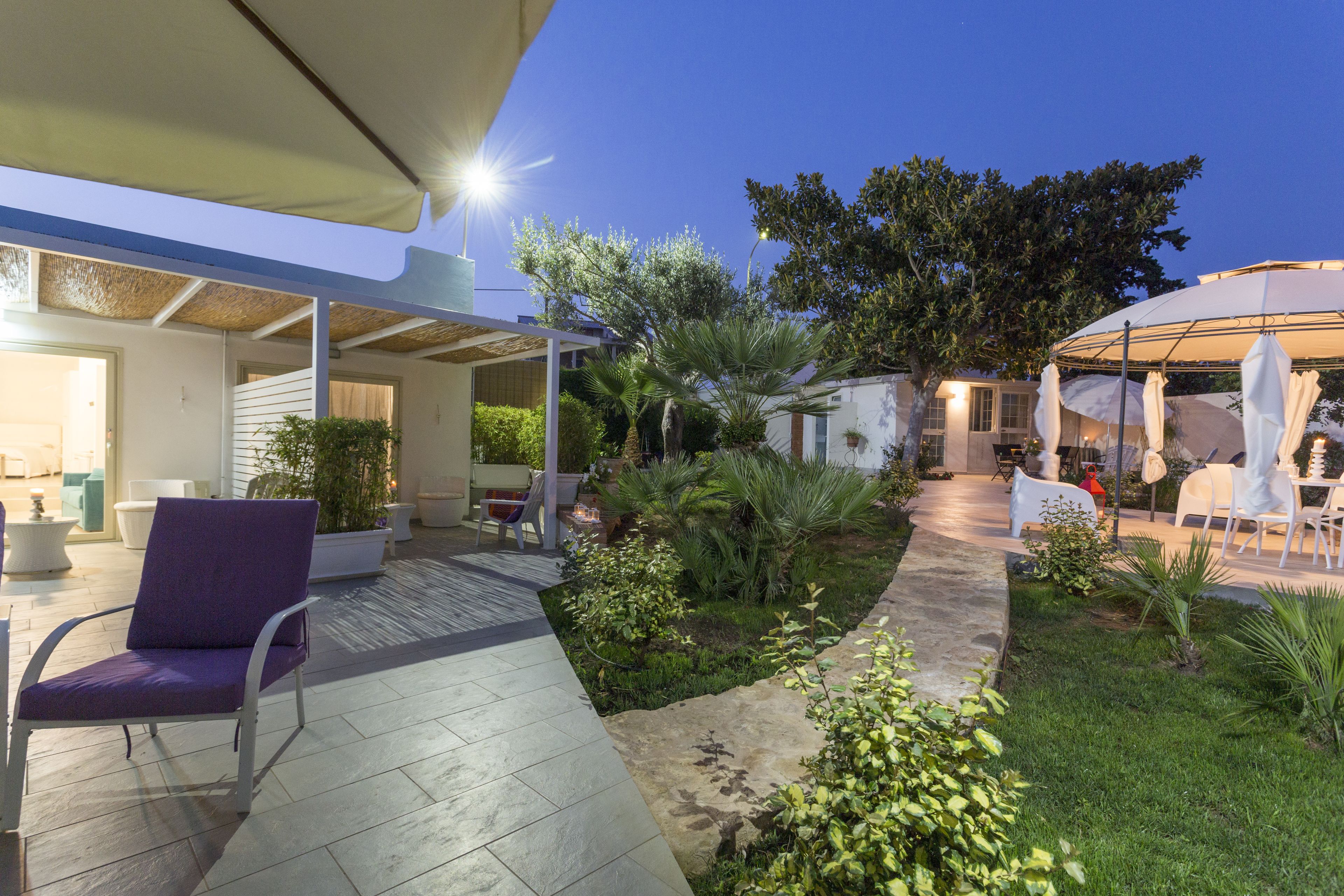 A patio area with a chair, a small garden, and a covered seating area.